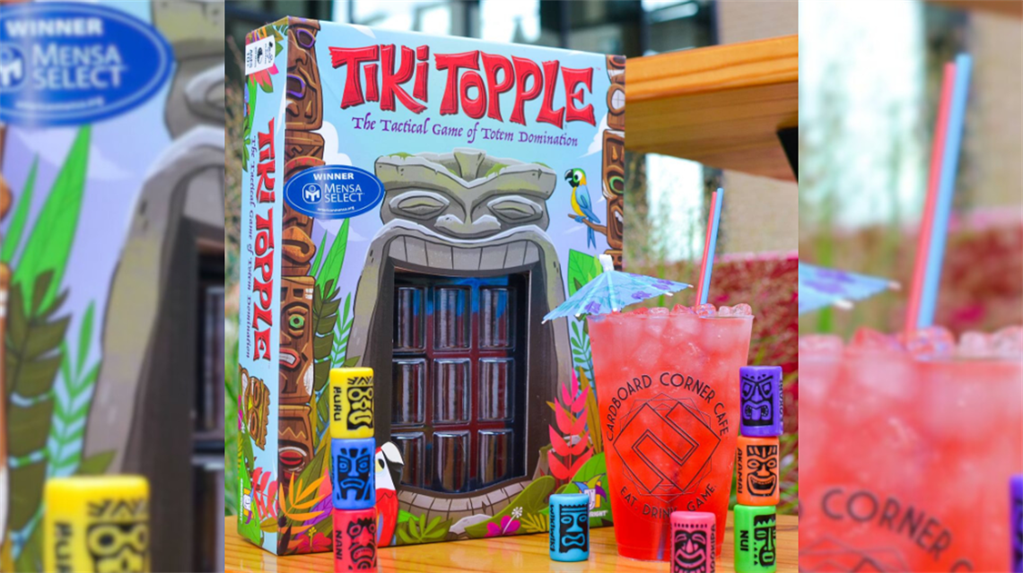 Tiki Topple board game set on table with specialty drink from Cardboard Corner Cafe.