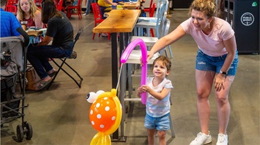 Mom and daughter holding fish-shaped balloon art