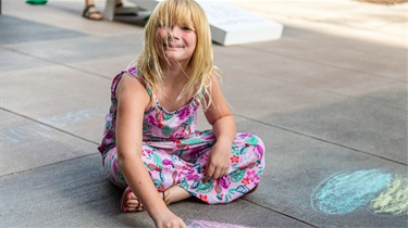 Young girl drawing on ground with sidewalk chalk