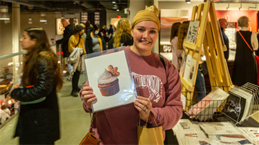 Customer holding a print from Sip, Mingle & Jingle event