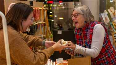 Vendor and customer smiling and exchanging product at Sip, Mingle & Jingle