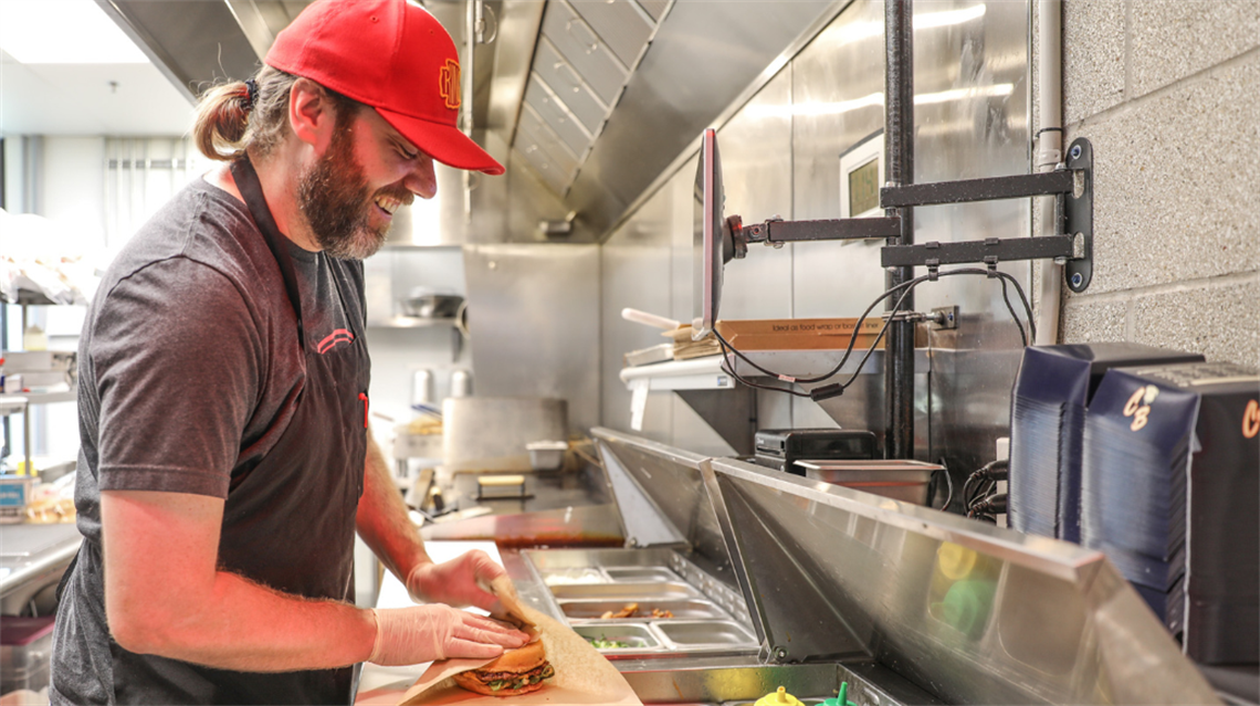 Chef/owner of Cosmo Burger, Jacob Kruger, preparing burger inside merchant stall