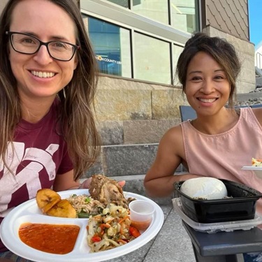 Two ladies eating African Dream Cuisine outside on the patio by Instagram user @urbanhikeskc
